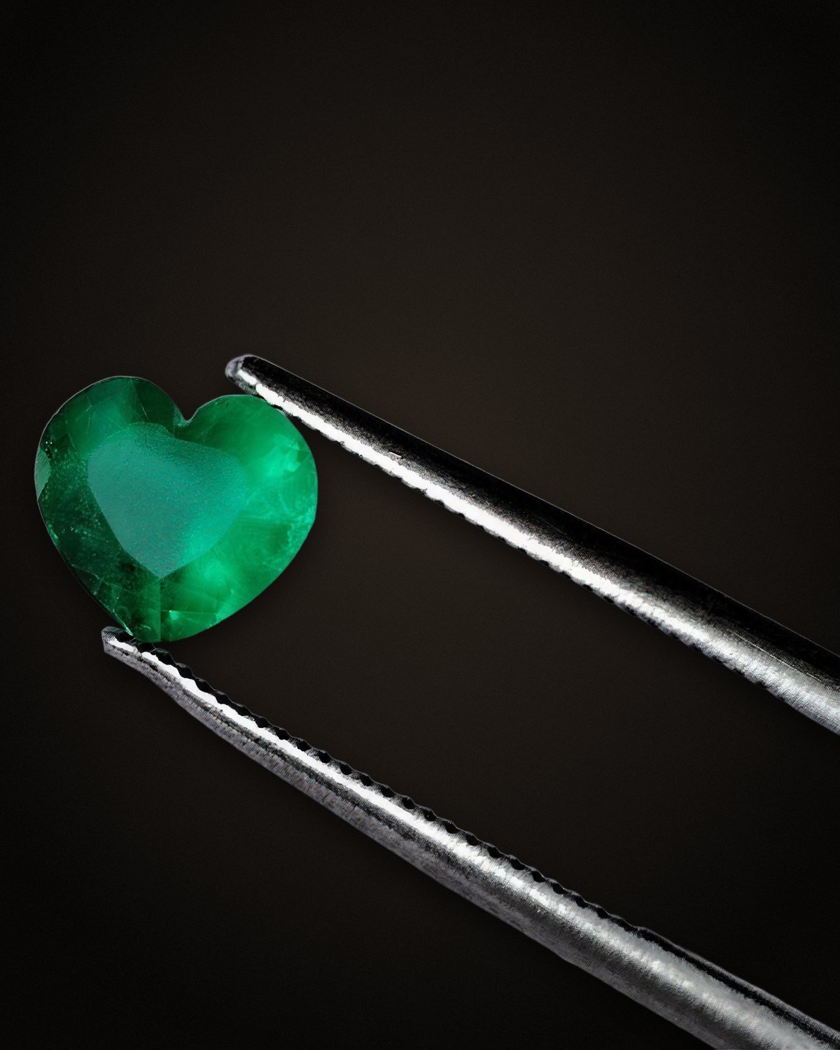 Esmeralda talla corazón sostenida con pinzas.